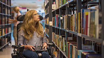 Woman in wheelchair in library; Internet & Mobile Hotspots for Libraries