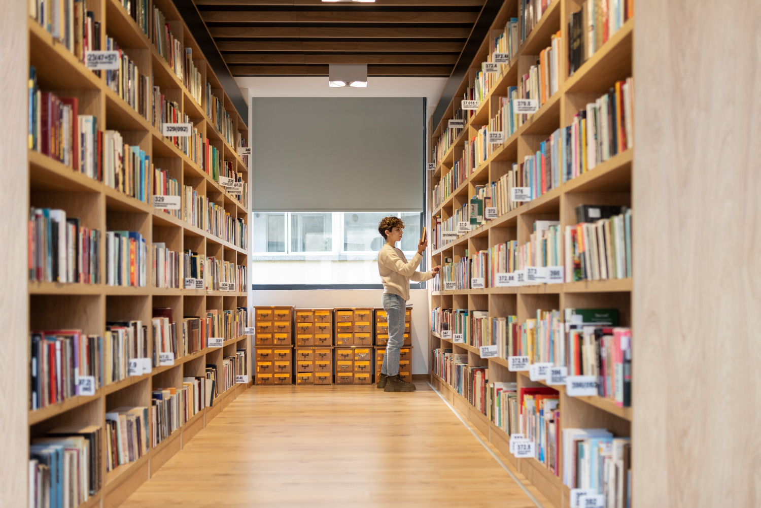 A patron reaches for a book in the quiet aisles of the Kansas City Public Library, surrounded by endless shelves of knowledge—symbolizing how hotspot lending extends library resources to homes for education and equity.